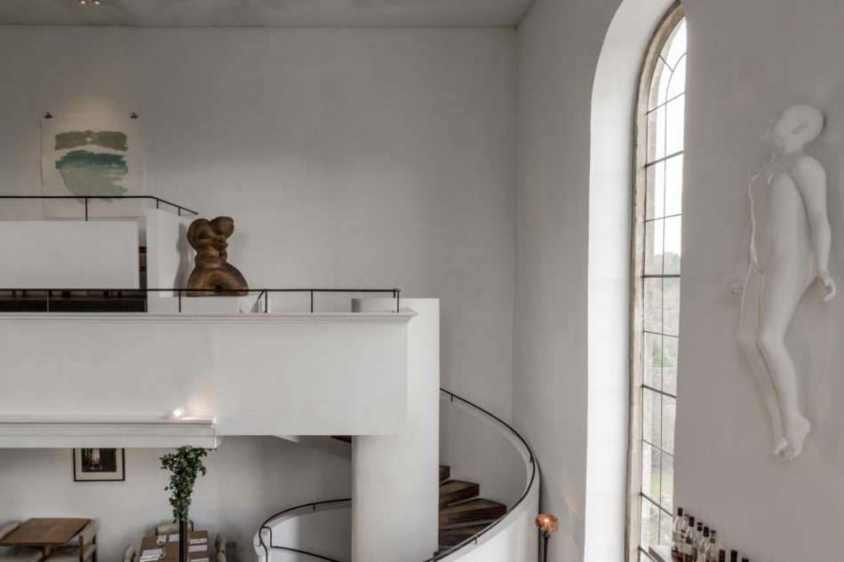In the interior, “materials are limited to reclaimed oak, local Doulton stone, simple blackened wrought iron fittings,” the architects say. Faith by Lucy Glendinning is on the wall to the right. Photograph courtesy of The Modern House.