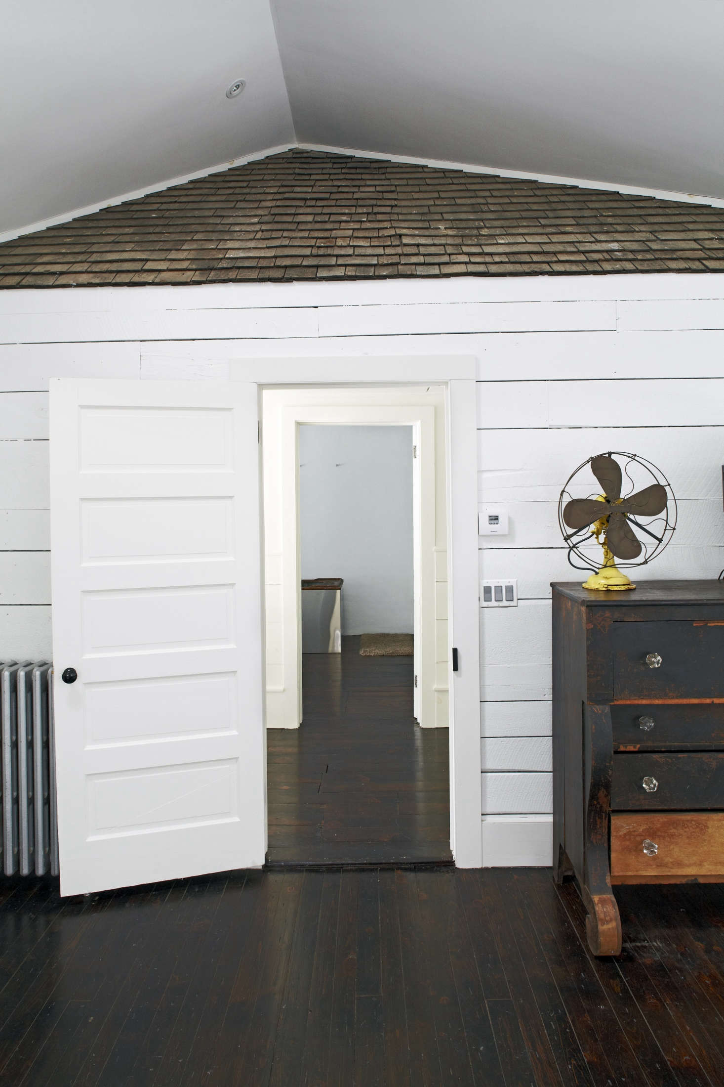 A shingled eave (featuring the house’s original cedar roof shingles) adds an outdoor touch in the master bedroom.