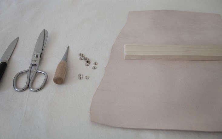 Step 1: Flip the leather over so that the inside of the hide faces up. Sand your pieces of wood, place atop the leather, and eyeball how you’ll wrap it. Measure, mark a pattern, and then cut to your liking.
