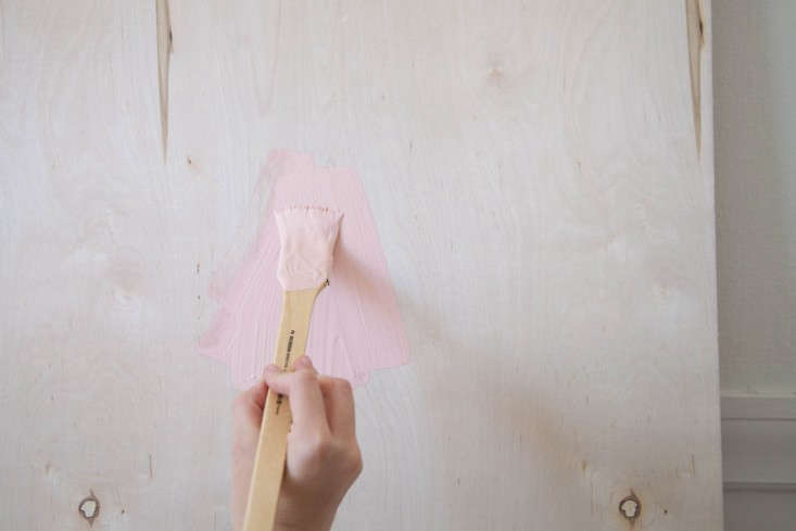 Step 1: Stand your panel of wood up against a wall on top of a painter’s drop cloth to catch any drips. Begin painting your board by brush or roller (your choice).