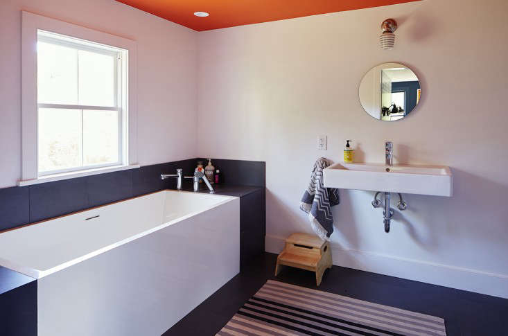 In the bath of an 1880s farmhouse in upstate New York, a monochrome rug balances out the brightly-painted ceiling. See Hudson Valley Hues: At Home with an Inventive Textile Designer.