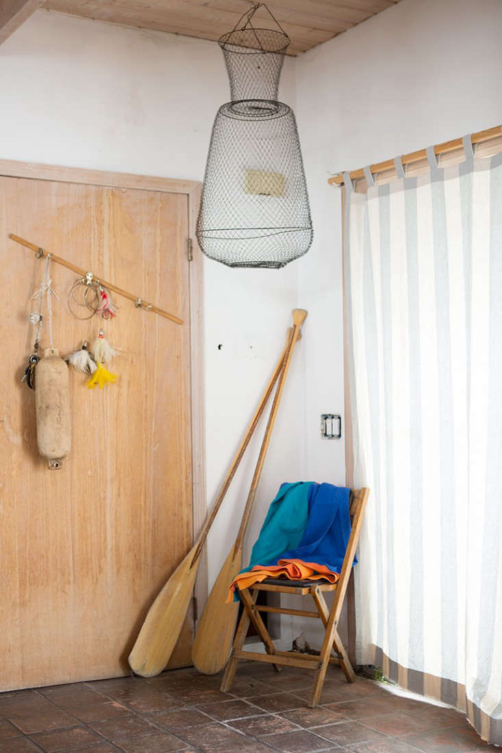 A curtained sliding glass door leads to the entry hung with a fishing trap. That