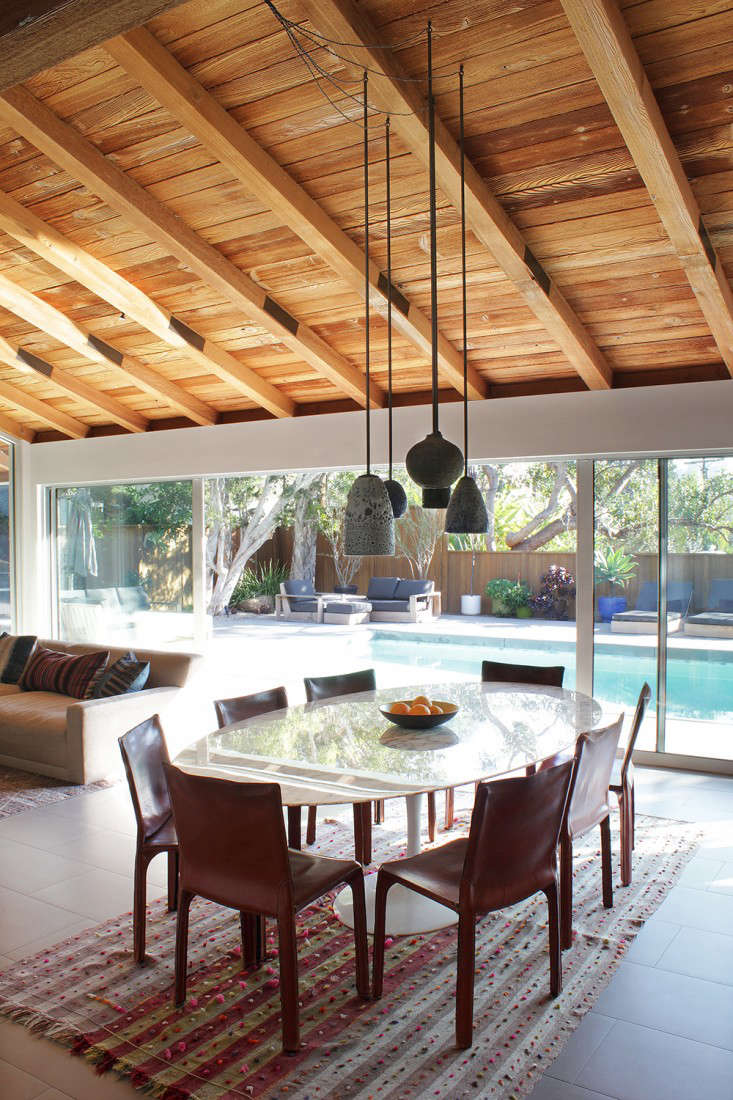 This is LA: The open living room/dining room overlooks the pool. Adam Silverman ceramic pendant lights were previously hung throughout the space; to create a focal point, Todd clustered them over the Saarinen dining table.