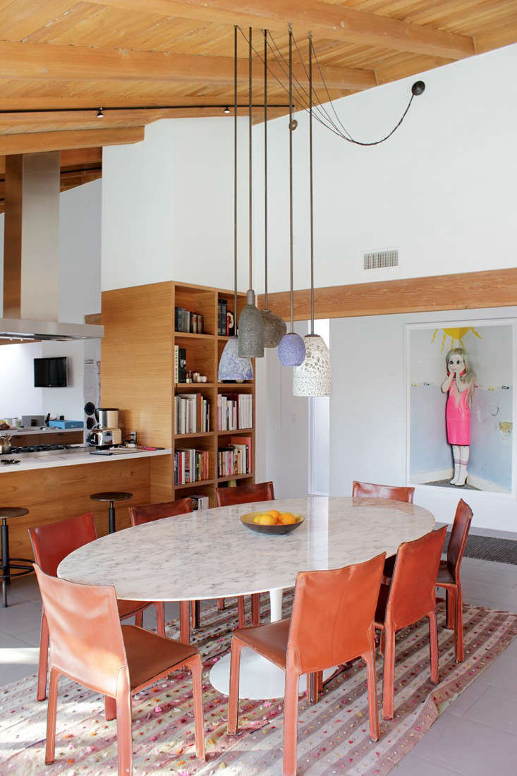 The table stands next to the U-shaped kitchen, which architect Julie Hart opened up to the dining room. After taking down the wall, she added built-in bookshelves that conceal the refrigerator on the other side. The photograph is by artist Laurie Simmons, a friend of Carla’s (and mother of Lena Dunham).