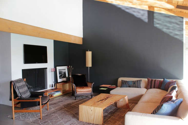 The living area is set off by a gray-painted wall and sofa custom designed by Nickey Kehoe. To connect the fireplace with the room, Todd inserted a two-tiered ledge/bookshelf made of Douglas fir.