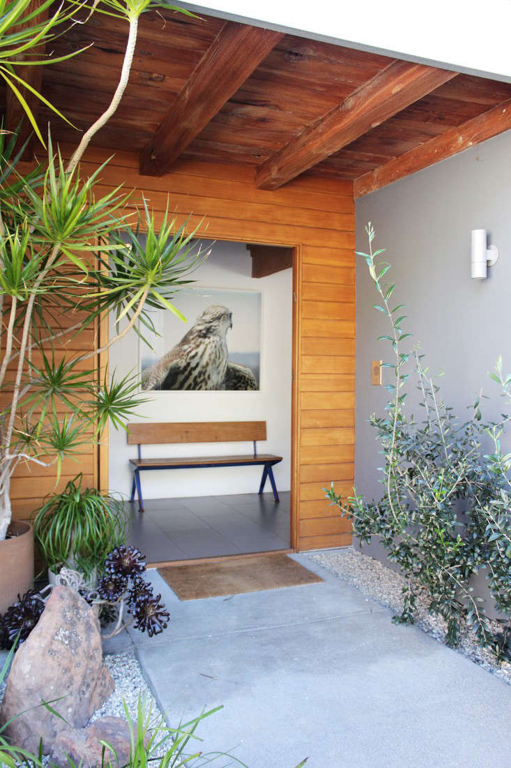 A sheltered garden leads to the entry, furnished with a Jean Prouvé bench. See it and more in 10 Easy Pieces: Modern Wooden Benches with Backs.