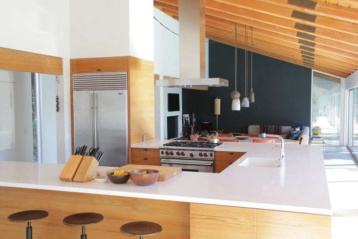 On the other side of the bookshelves, the fridge is wrapped in wood, connecting it to the teak cabinets and exposed beams. The countertop is made of CaesarStone–read about this miracle material in Remodeling 101: Engineered Quartz.