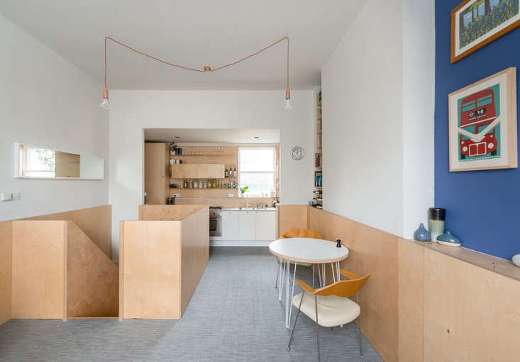 A plywood chair rail wraps around the kitchen and dining rooms in A Compact Apartment in London by a Craft-Oriented Architect.