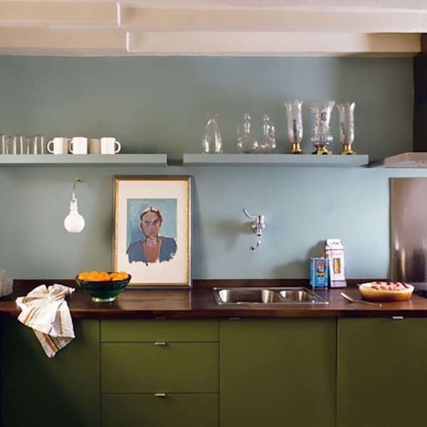 A kitchen in Paris by architect Philippe Harden, a portrait propped on the wood counter picks up the color scheme of pale blue and olive green.