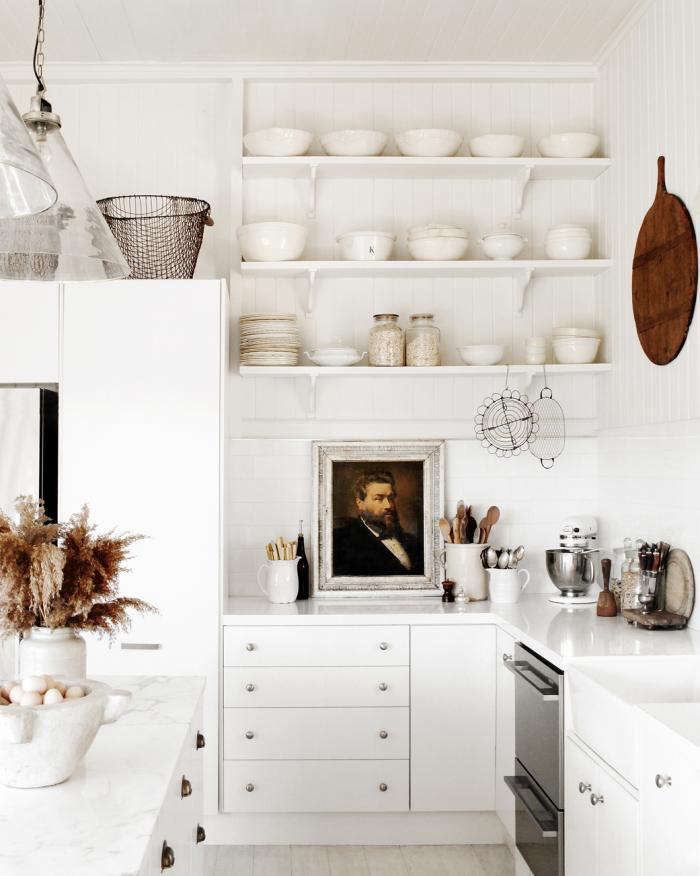 A distinguished portrait is on display amid wooden spoons and pans in a stylist