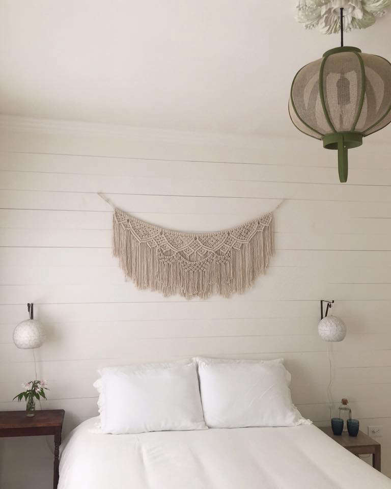 A macramé artwork hangs over one of the beds.