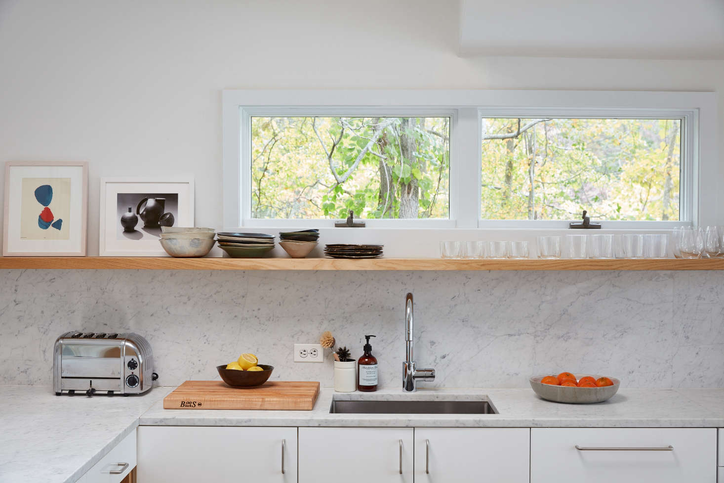 “We love open storage to showcase our collection of ceramics,” Jones says. Among her favorites: earth tone ceramics by Joan Platt (on shelf) and a concrete bowl (filled with oranges) by Clam Lab. The Dualit toaster was purchased on Amazon.