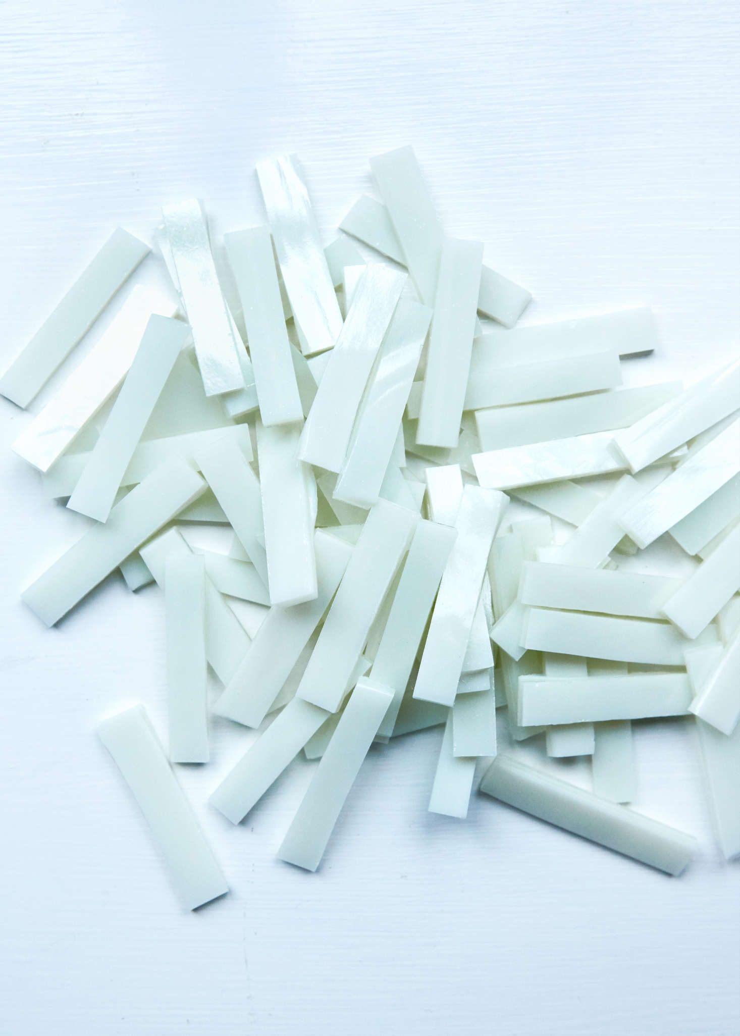 Glass tiles, known as tesserae, are handcut from sheets of pressed glass of uniform width (Myers sources hers from Spectrum and for this chose a streaky opal). The process involves scoring the glass on both sides and then using a nipper to break it into pieces.