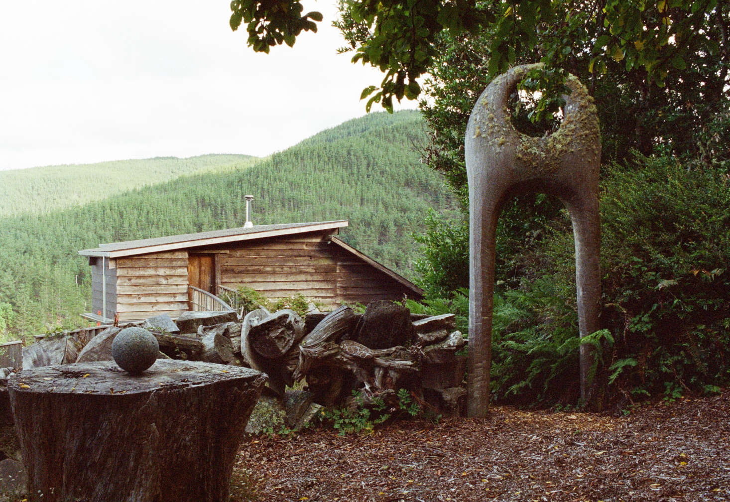 Blunk carved the property’s entry arch from one redwood trunk. On a stump, he perched a naturally formed rock sphere found in the nearby Stanislaus River. Blunk made the property’s sculptural “Scrap Wall” by stacking redwood and cypress slabs and driftwood chunks.