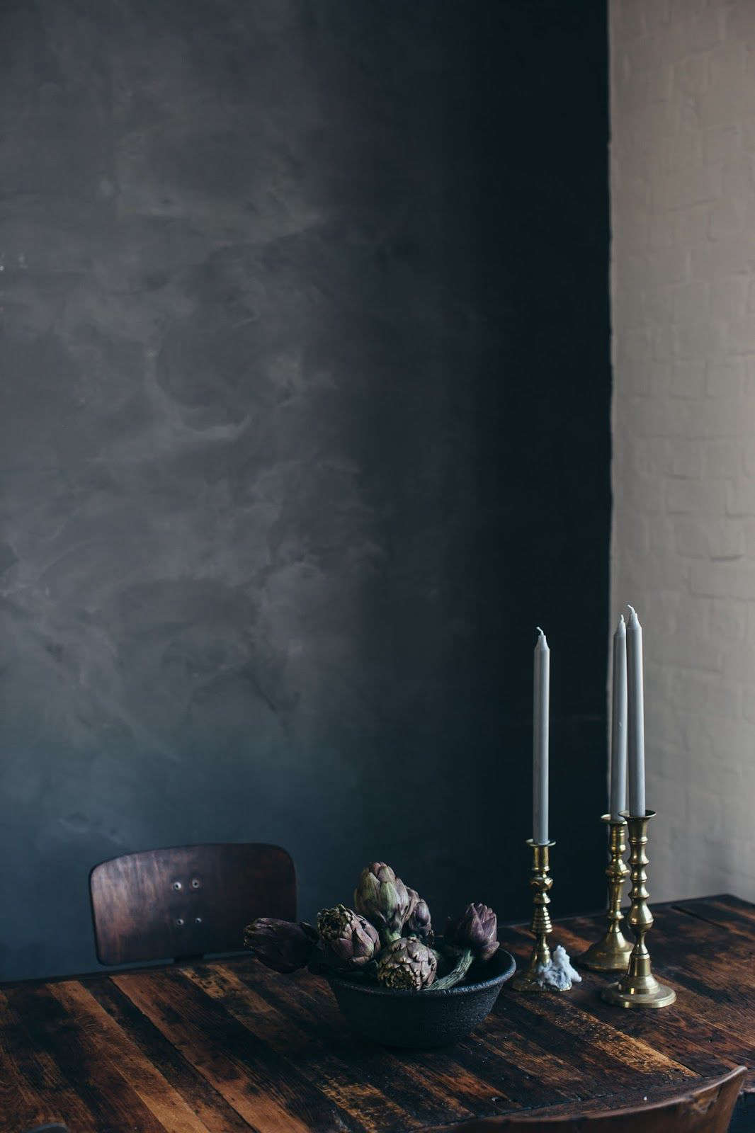 In the back of the room, an industrial dining table stands against a wall of Kabe plaster in a color called Chalk Board. Kabe says its tinted plaster is easy to apply and dirt repellent.