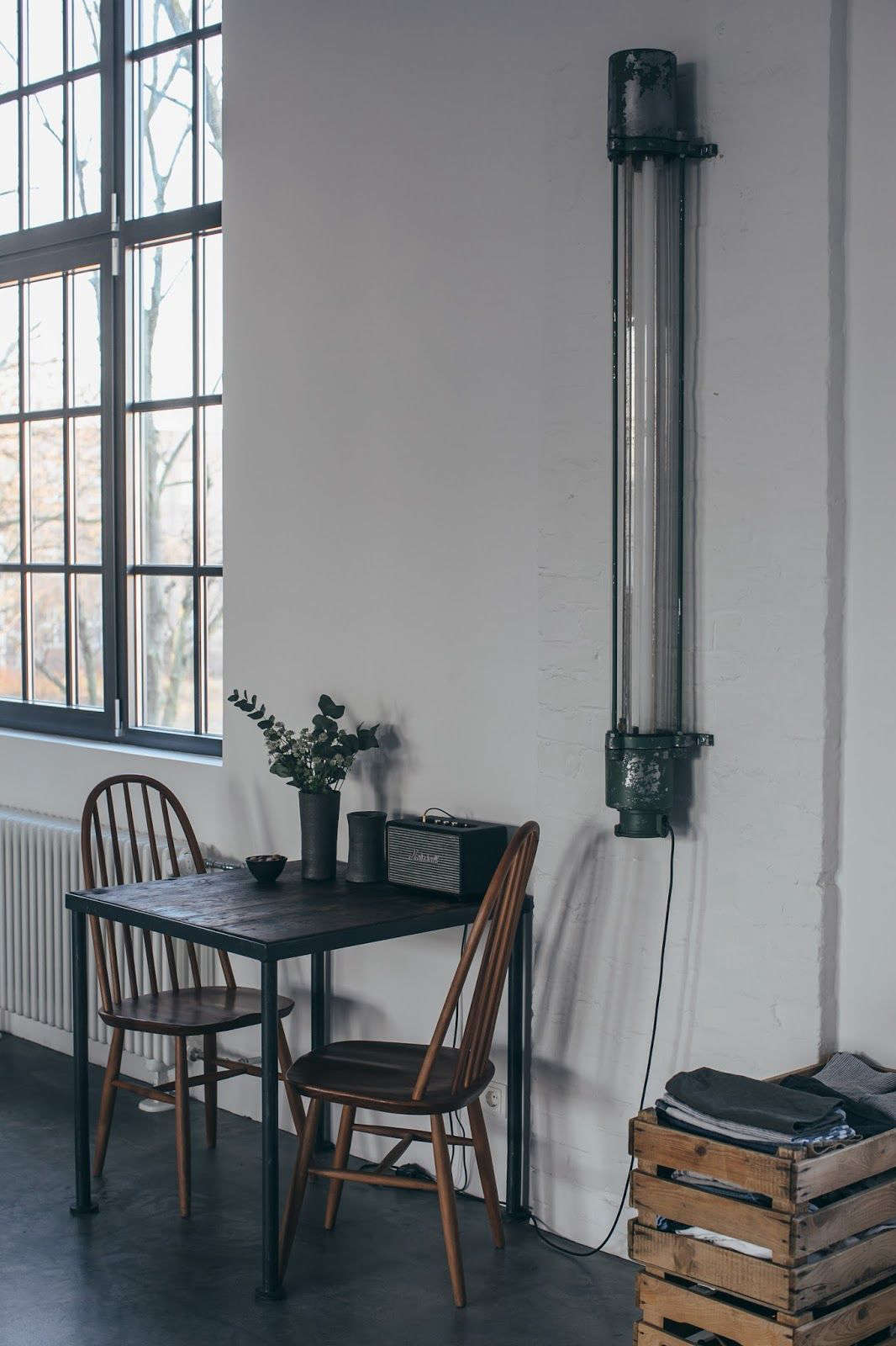 Above; A vintage factory light hangs next to a table for two with a pair of old Windsors.