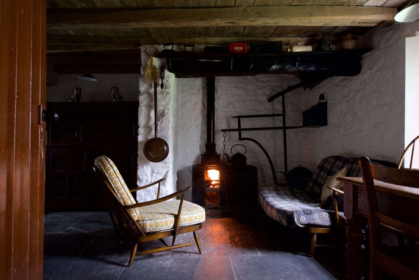 A wool blanket serves as makeshift slipcover in The Welsh House: Slow Living in a Traditional Cottage, Available for Rent, in Wales. Photograph by Will Venning for Remodelista.