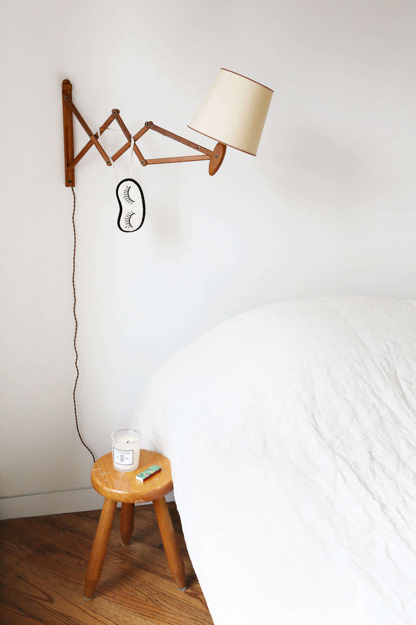 Javitch keeps a few wellness essentials by the bed: a candle and long matches. A sleep mask hangs from a vintage accordion wall lamp from Orange Furniture in LA.