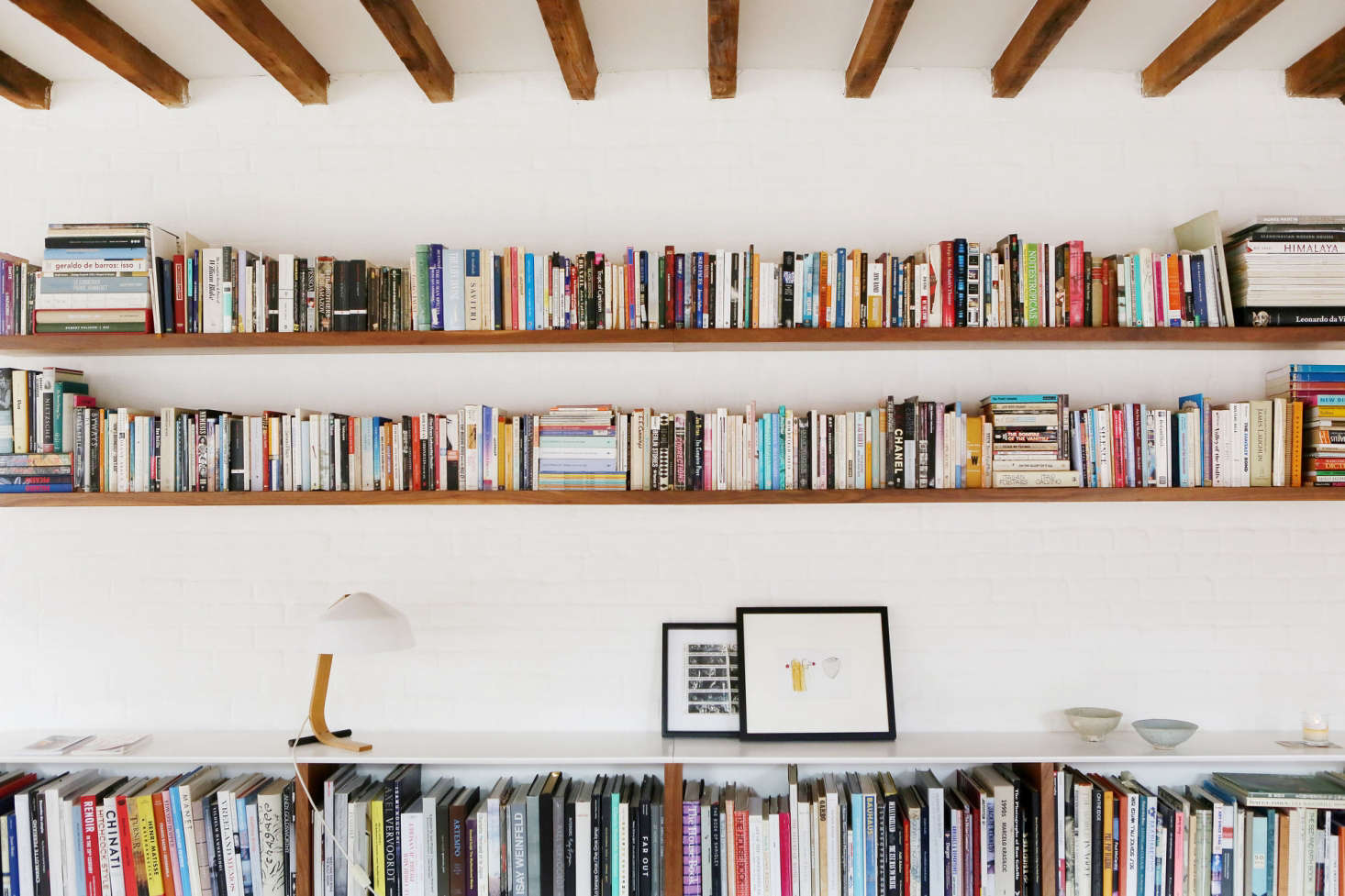 Built-in shelves replace freestanding bookshelves and create a display shelf for art and favorite objects. Long uninterrupted shelves feel expansive rather than cramped.