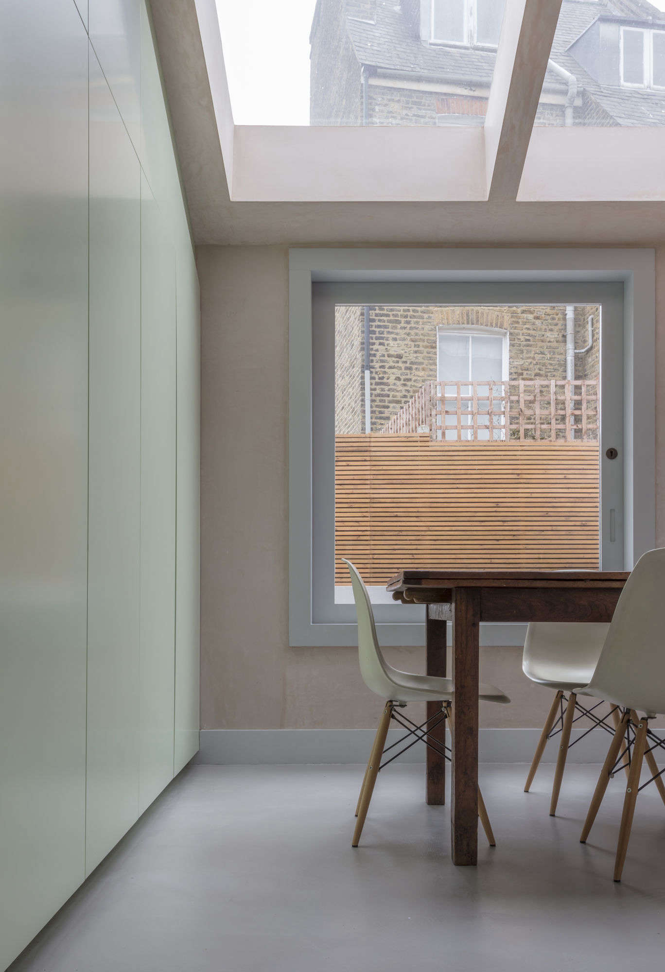 To keep the room clutter free, the architects included a long wall of seamless built-in storage in pale green spray-painted MDF. “It’s less expensive than laminate and doesn’t have that plasticky finish,” says Dumciute.
