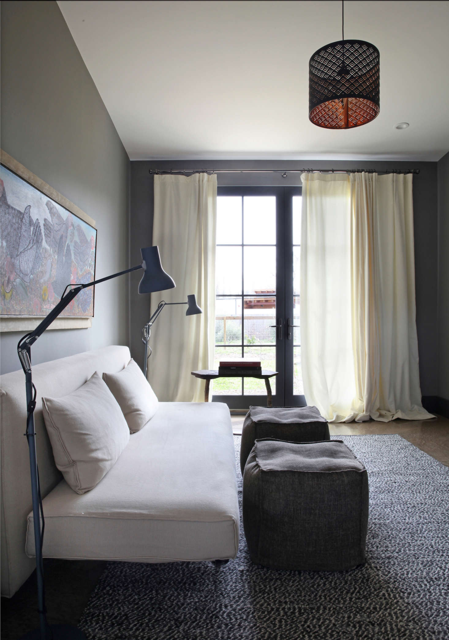 In the reading room, two Anglepoise lamps are angled over a Design Within Reach couch on an Ikea rug.