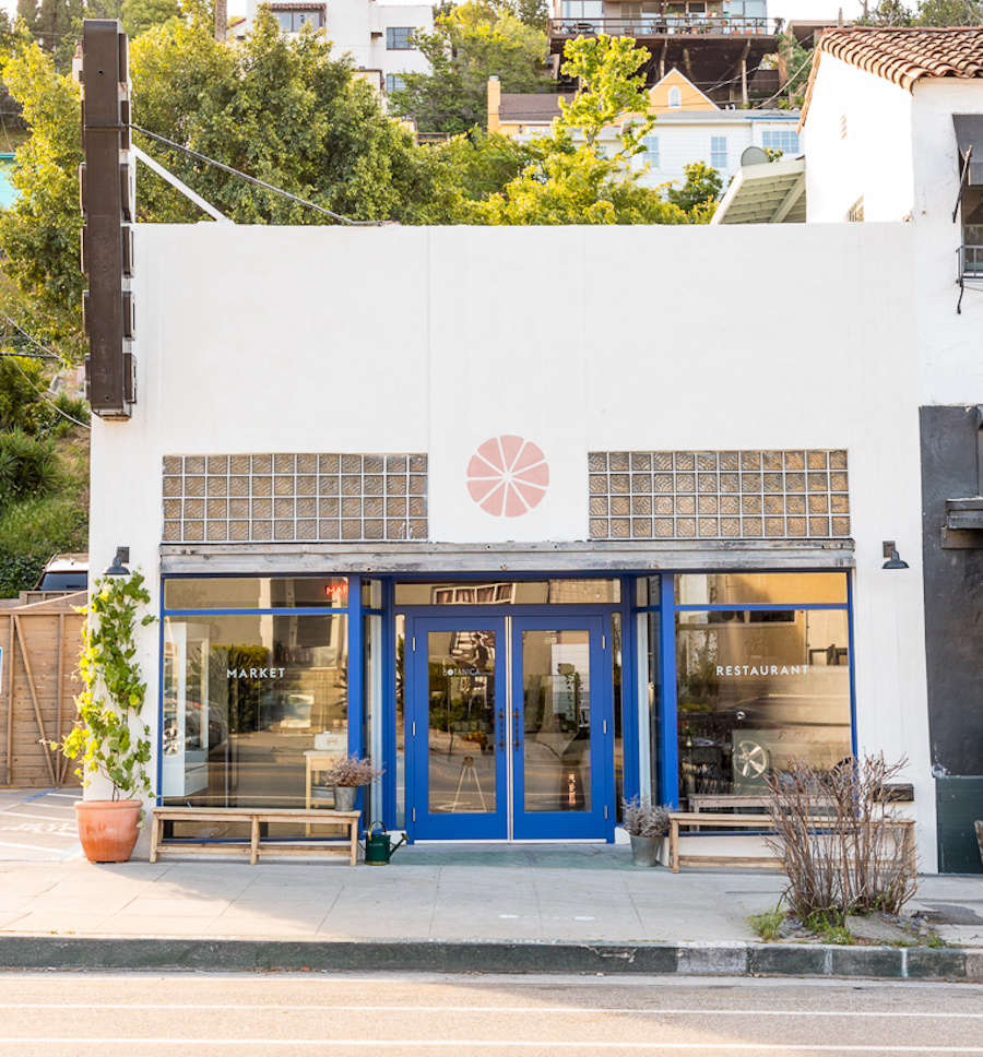 The combination restaurant and market has bright blue trim and potted plants outside.