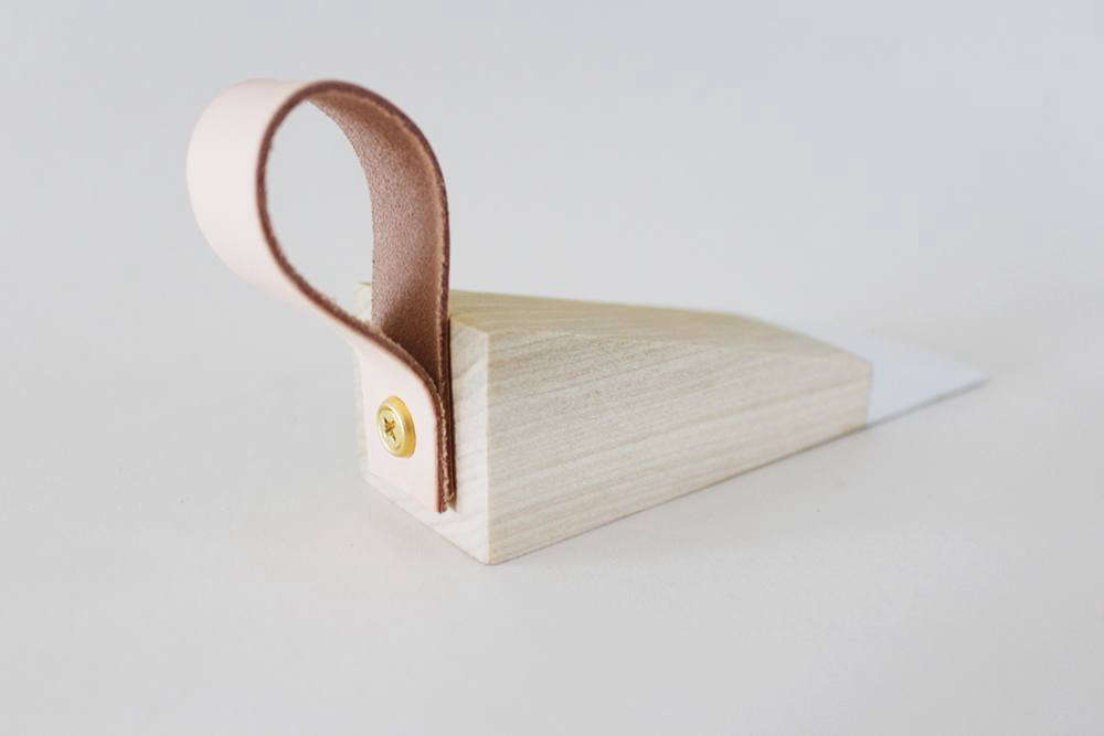Step 3: Drill a small hole through the center of the back end—Anna suggests using the other half of the scrap wood as a base. Use the drill to attach a loop of leather secured with the washer and screw.