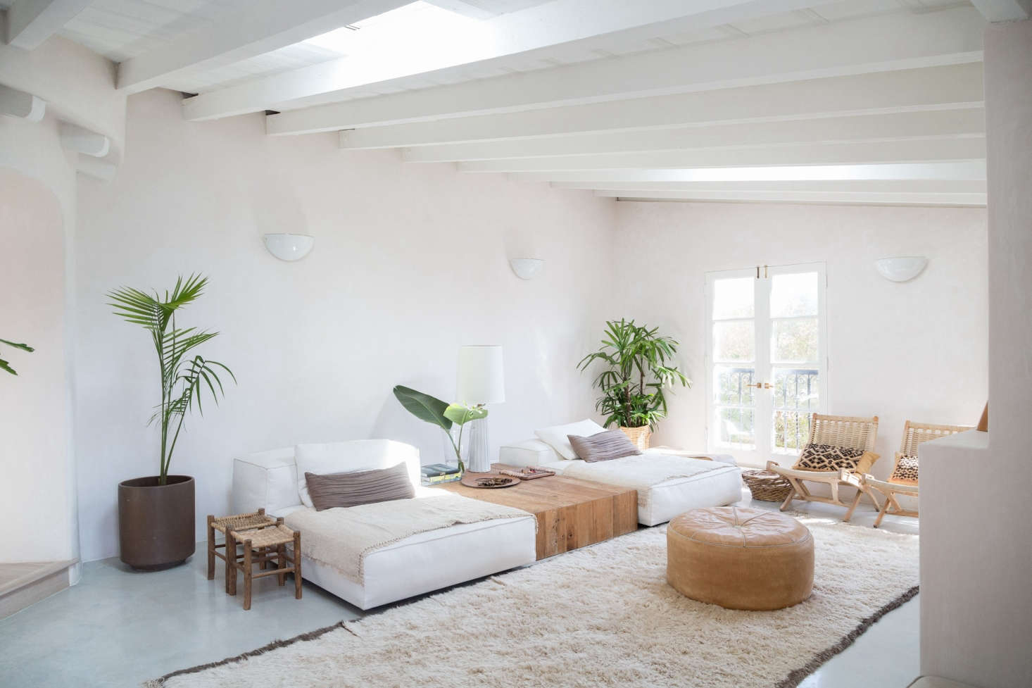 An airy living room channels laid-back LA living with low-slung white chaises (Living Divani modular sofas) and a custom white oak table. Golubovic found the midcentury woven chairs at a flea market in Chicago.