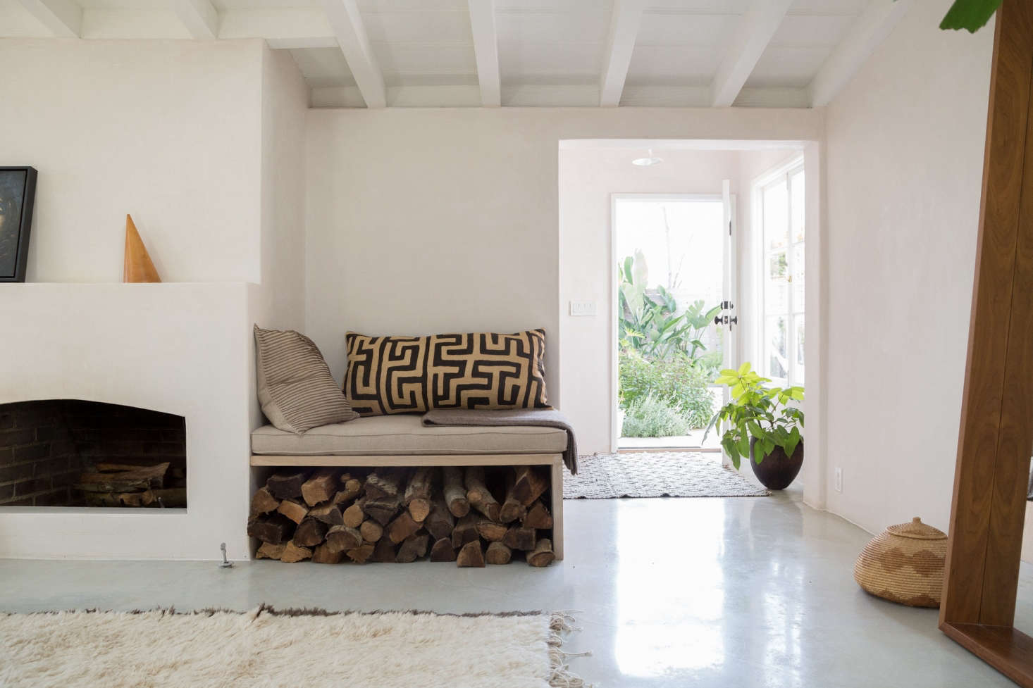 Golubovic updated the brick fireplace by creating a concrete front and then adding plaster over the top. A built-in bench alongside doubles as log storage.
