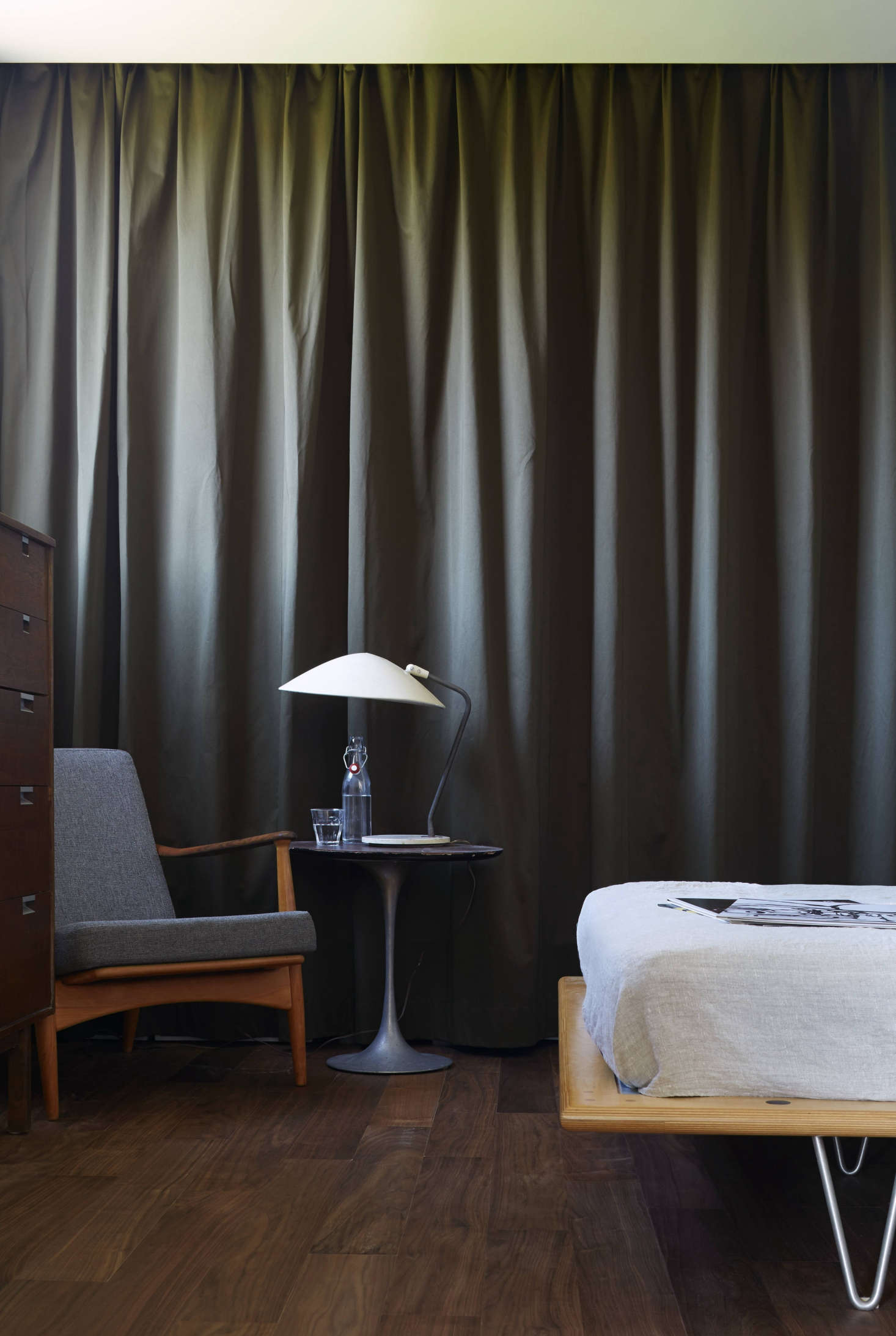 In the master bedroom, the closet is set off by olive-colored heavy cotton canvas curtains that hang from a ceiling track and conceal standard metal shelving. 