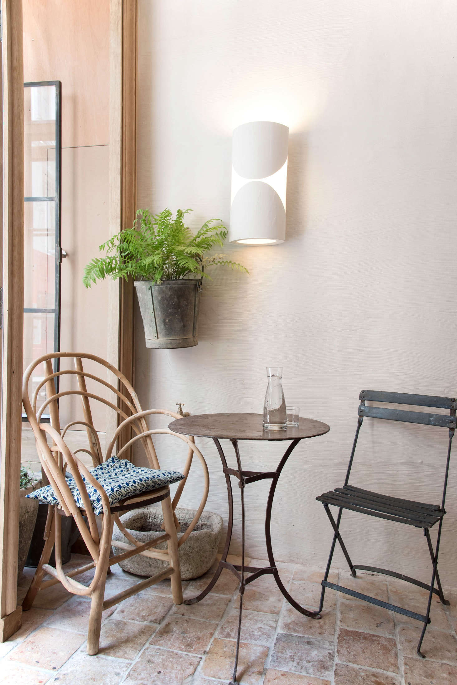 The front terrasse room has the feel of a laid-back garden in a generations-old family estate, thanks to mix-and-match vintage garden furniture that de Villeneuve sourced from flea markets and brocantes in the South of France. For easy charm, follow suit: Mix indoor with outdoor chairs, cane with metal, and a cushion or two. (The plaster lights were designed by Champsaur.)