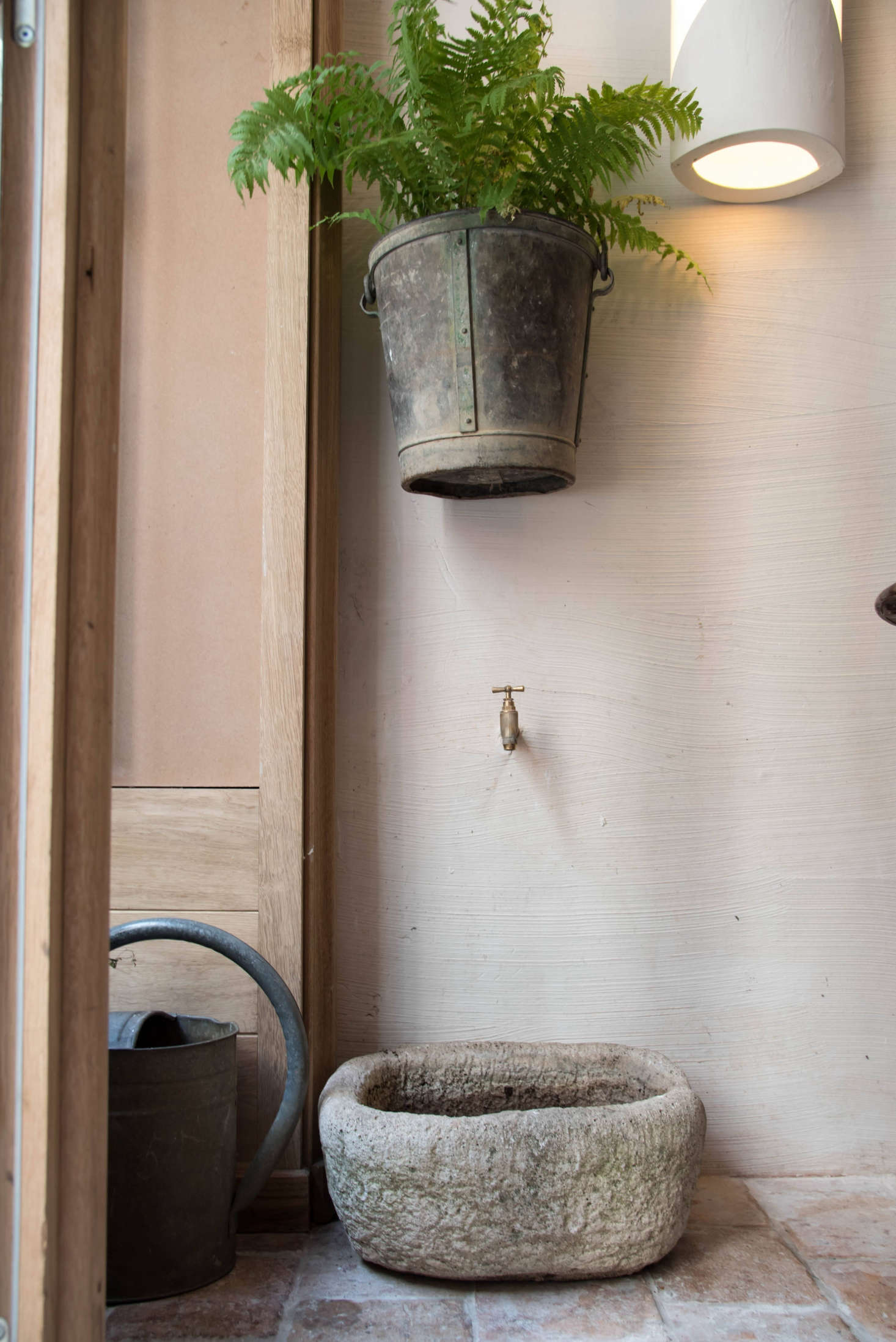 For a respite from the heat, add elements from the garden. In a quirky vignette by the front window: A copper spigot in the wall is positioned above a stone basin, a flea market find which will soon house herbs.