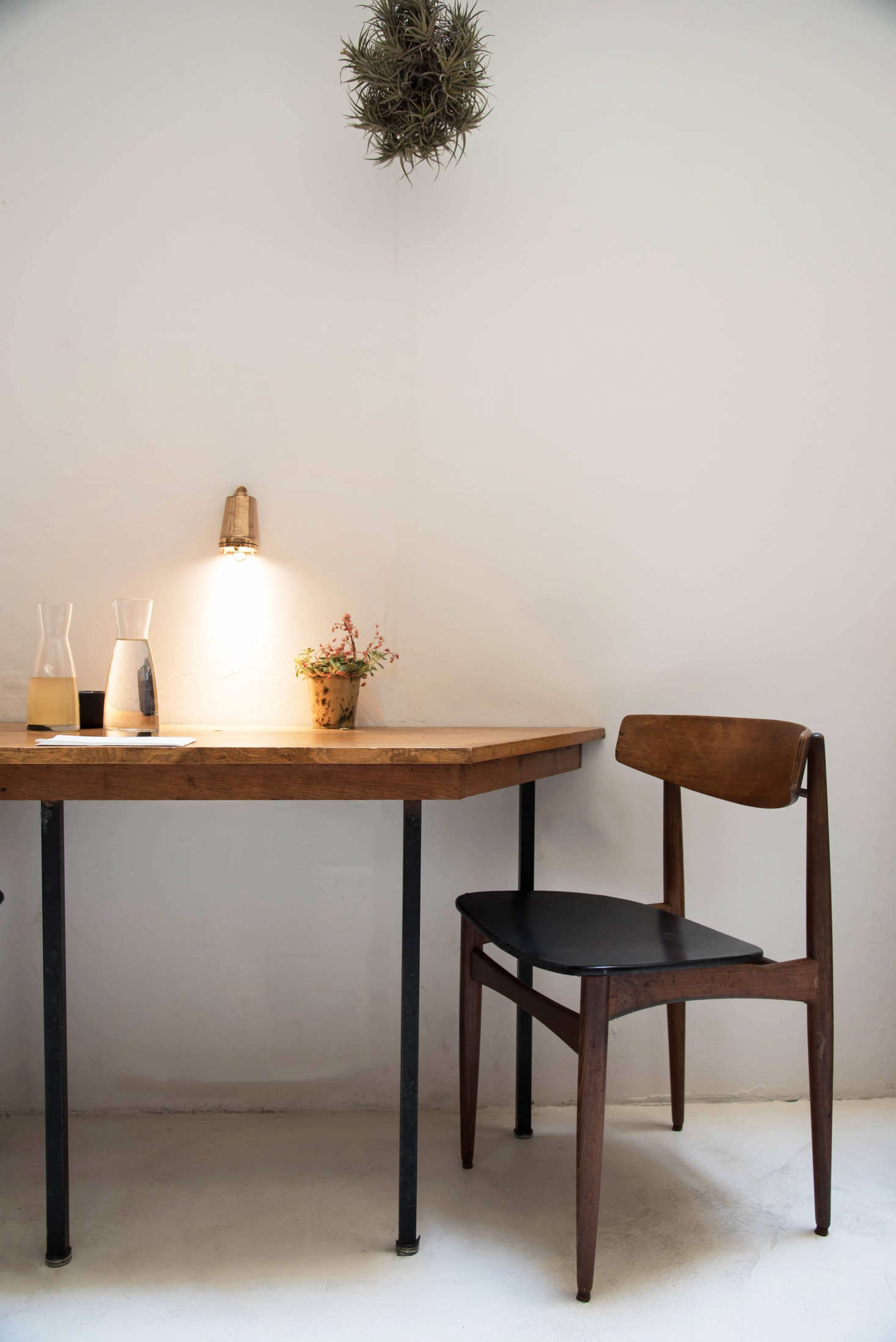 In a more polished, streamlined section of the cafe (with furniture by Champsaur), statements come from small details, like a bundle of greenery hung above a table. To get the look, consider hanging a single detail—a small painting, a bunch of greens—on an otherwise empty wall.