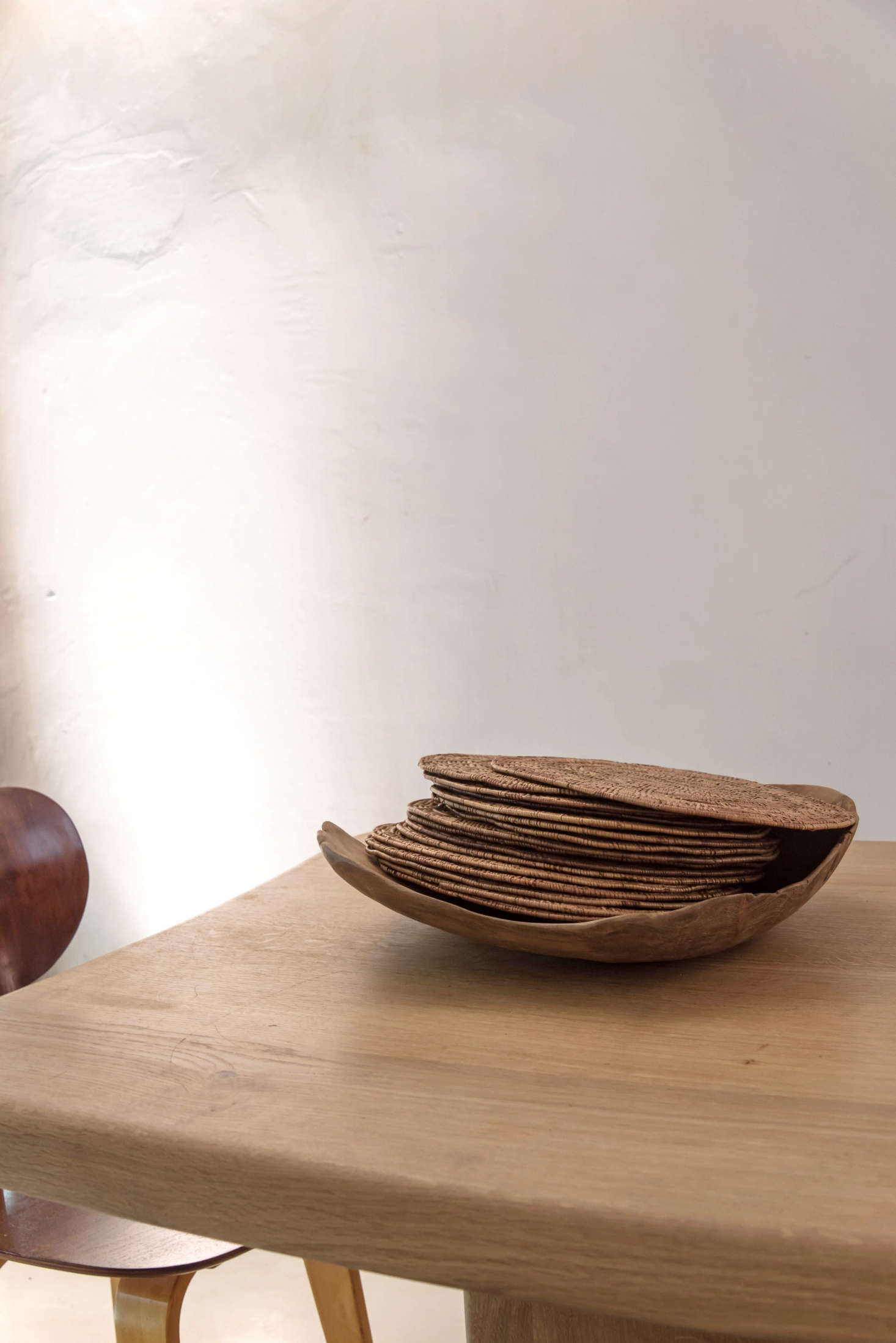 For an impromptu table setting, stack napkins, placemats, and glassware on the table and set out vintage baskets heaping with flatware. Here, woven placemats become a design object when set in a wooden bowl. (De Villeneuve sourced design elements that would feel “in line with the products that I was sourcing: grains, flour, olive oil, almonds, etc., coming from Sicilia, South of France, Mallorca”—the placemats are from Mauritius.)