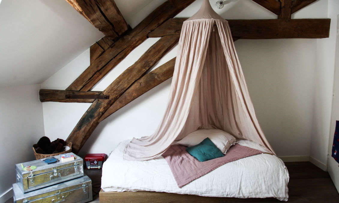 A hanging cotton Bed Canopy is paired with linen bedding, all from Numéro 74 and available from Smallable (see The Smallable Apartment in Paris for more). The steel trunks are Chinese.