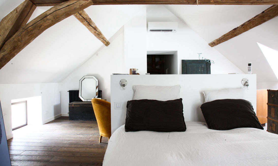 A floating bed frame under the eaves partitions off the sitting and sleeping sections of the master bedroom.
