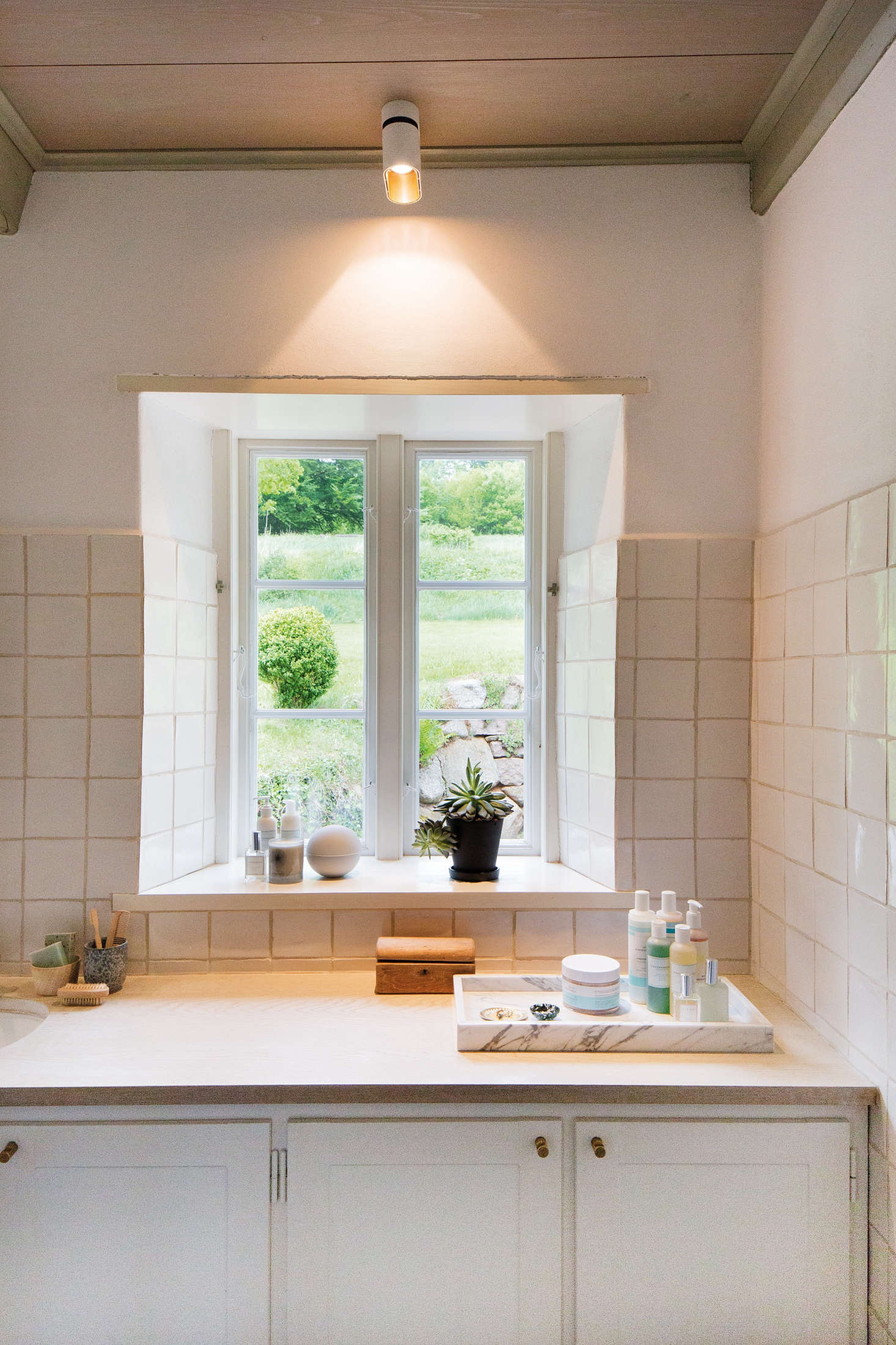 The bathroom design mimics the look of the kitchen, with the same handmade tiles, wood counters, and brass pulls.