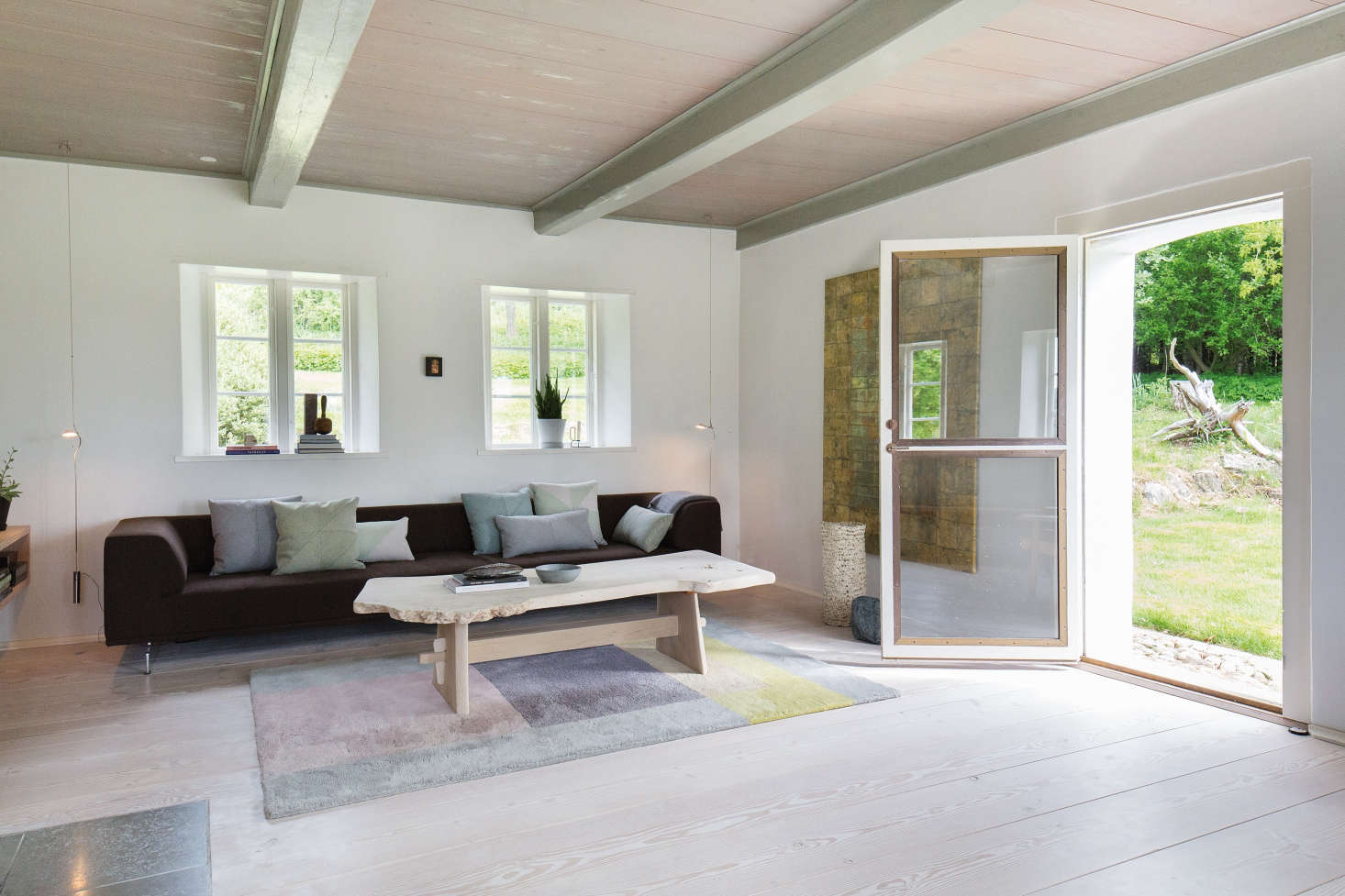 A living space on the main floor is decorated with modern furniture and textiles. The new door to the outside is double-paned glass reinforced with metal.