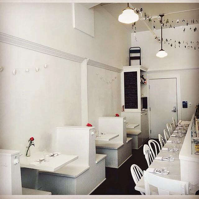 The small interior features two-person booths with built-in tables. Garlands of dried flowers and leaves are strung from the ceiling.