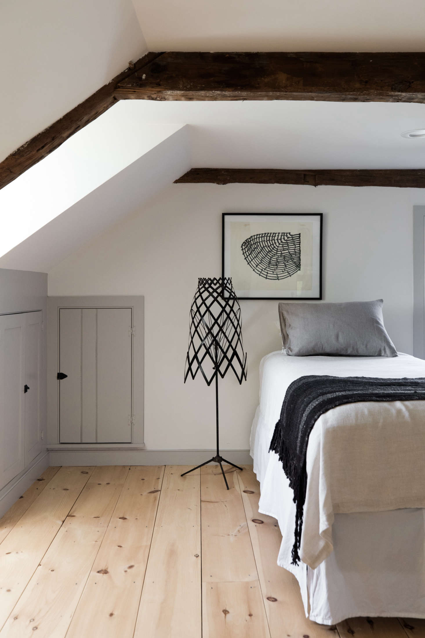 In a narrow bedroom, Esteves preserved the under-eaves cabinets, which his mother uses to store spare blankets.