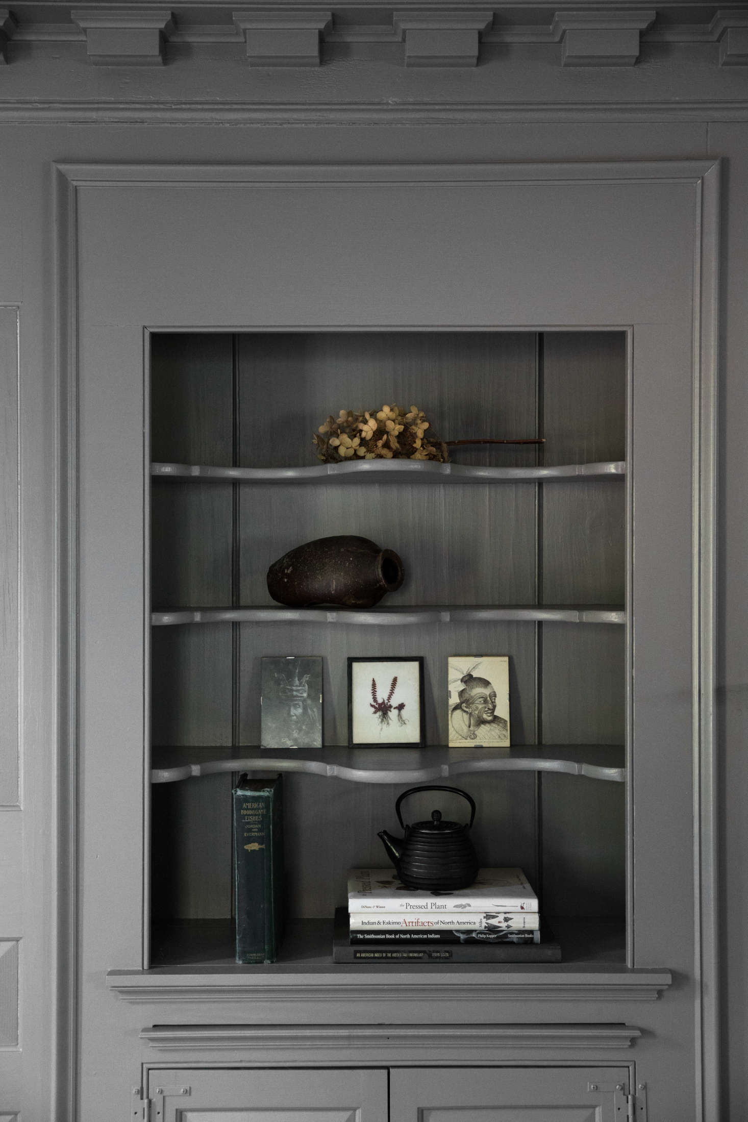A built-in hutch, painted gray, holds objets d