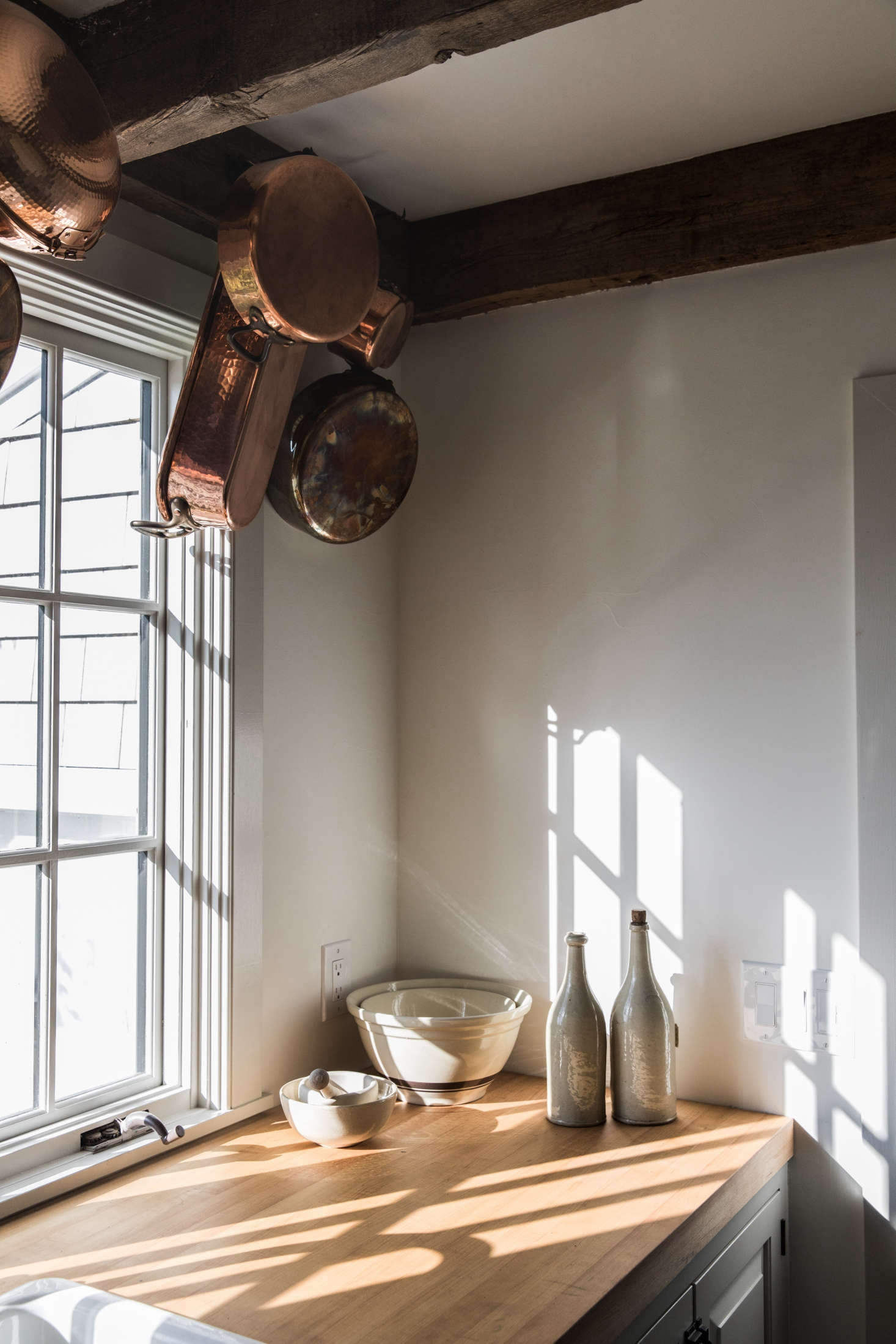In another corner of the kitchen, copper pans hang from iron wall hooks affixed to the timber rafters.