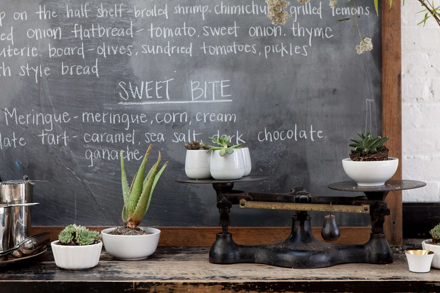 A vignette on a sideboard: A vintage scale—salvaged from Ted & Honey—”is used to store sugars, stirrers, and many a muffin plate.” Incorporate, and repurpose, the unexpected and eclectic.