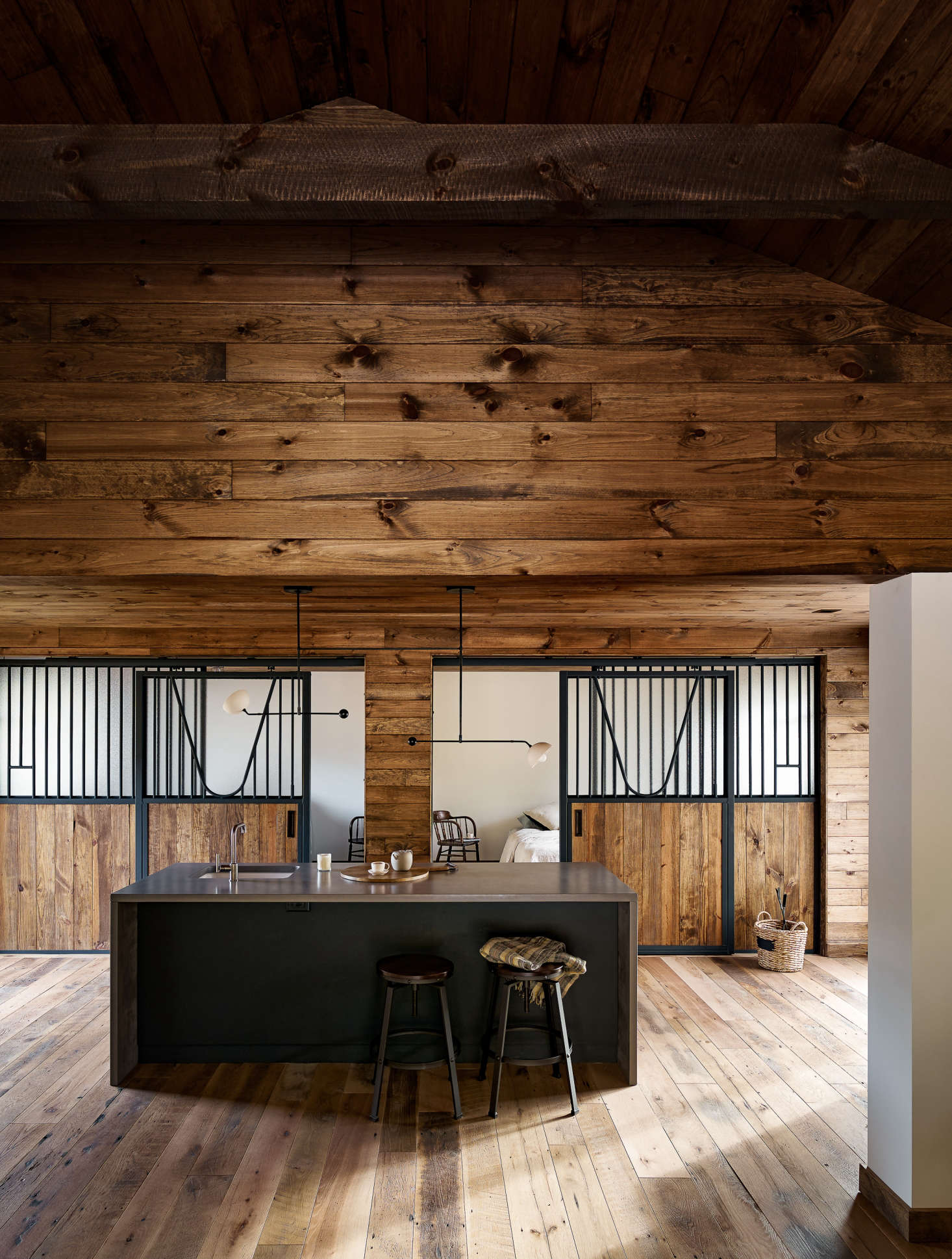 A small kitchenette with poured concrete countertops anchors the space. It has a sink and small fridge—just enough to host a party. The pendant lights above the island are General Assembly designs of unglazed porcelain and blackened brass.