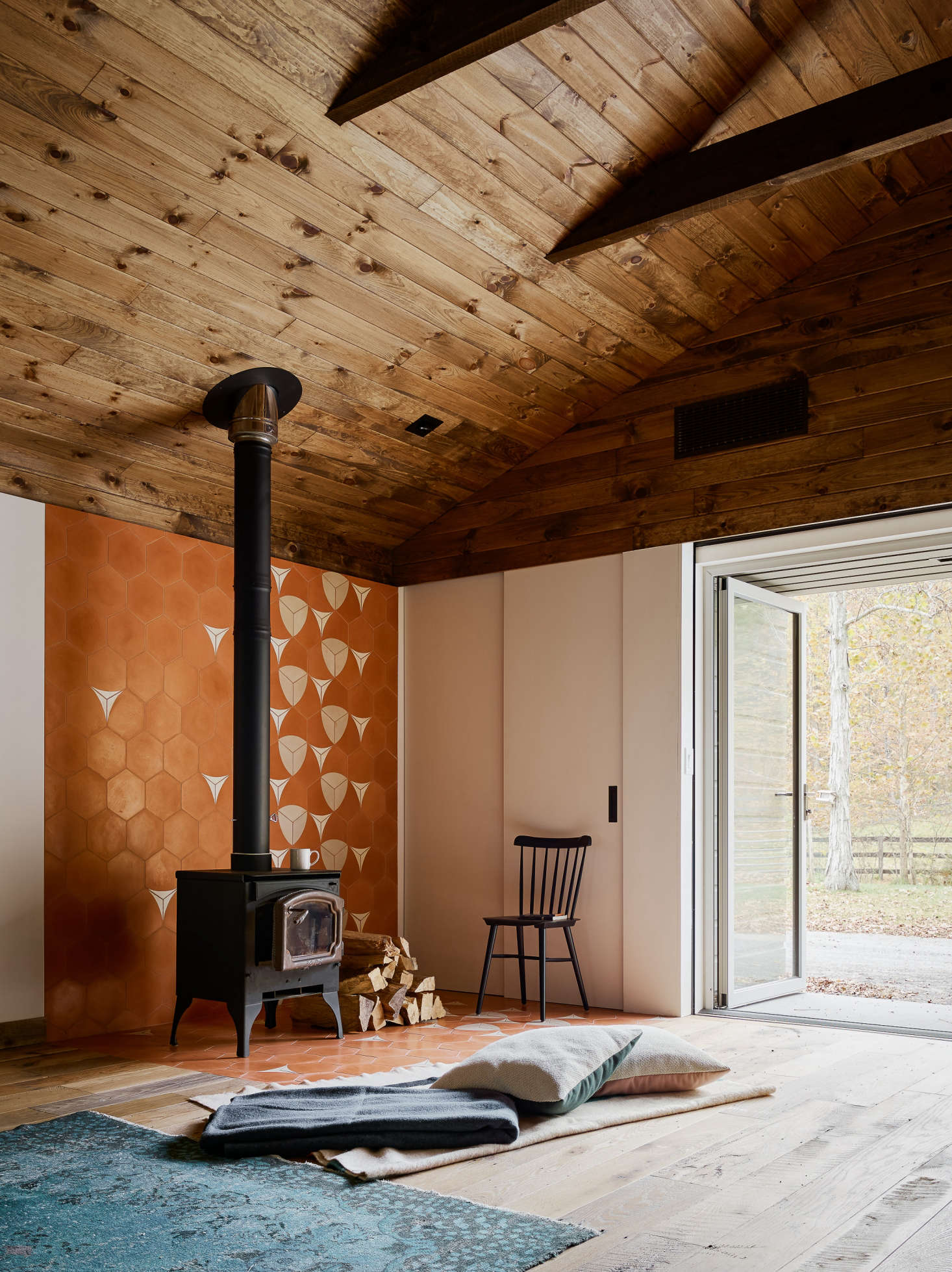 Adjacent to the sitting area is a woodstove with a tiled back wall and floor. “We used a bright pattern to define space around the fireplace,” said Zames, “in order to bring in light while still keeping things open.”