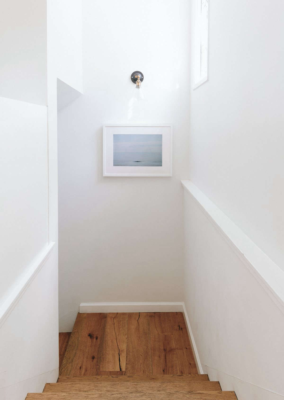 The artwork in the stairwell is an Emma Wood Print by photographer Marc Gabor—a collaboration between Jenni Kayne and Tappan ($655, framed). Hunter found the sconce on Amazon. The floors throughout the house are brushed white oak.