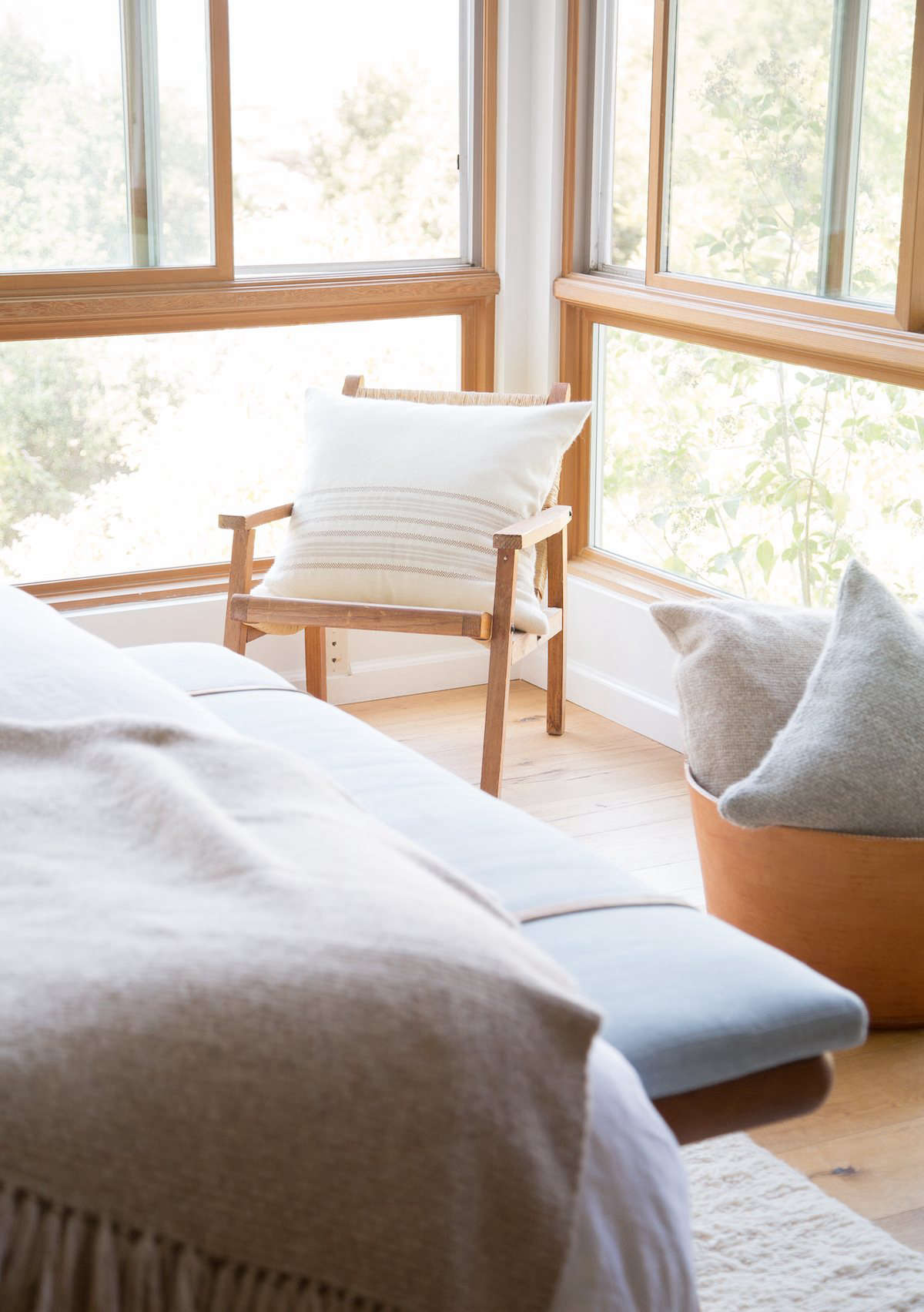 A leather basket from Jenni Kayne stores more alpaca basketweave pillows. At the end of the bed is a vintage wood bench from Lawson-Fenning in LA, covered in blue linen with added leather straps.