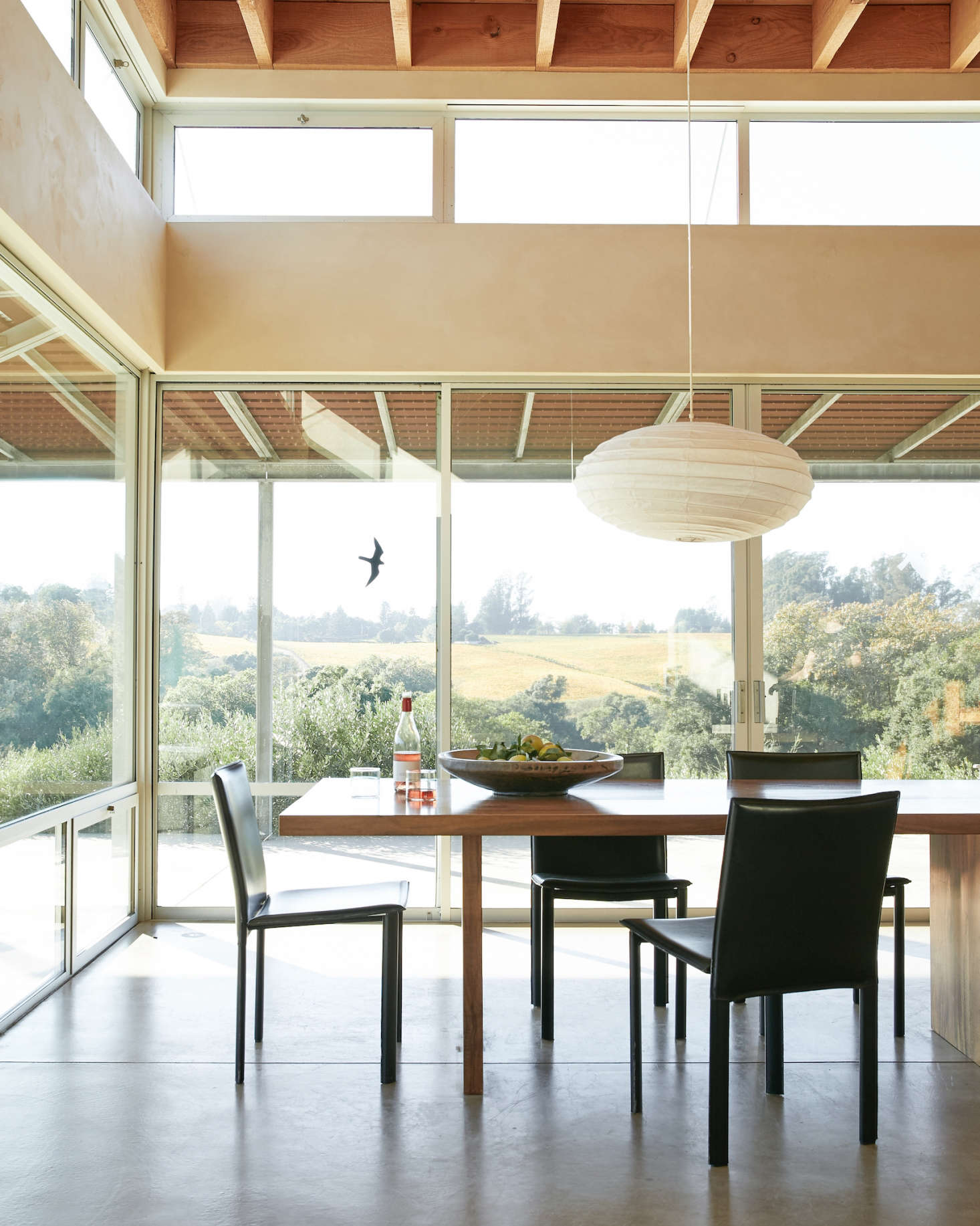 Next to the kitchen is the open-plan dining room, perched on the edge of the upper estate overlooking the vines. The dining table was custom-designed by Anding, fabricated locally using salvaged wood.
