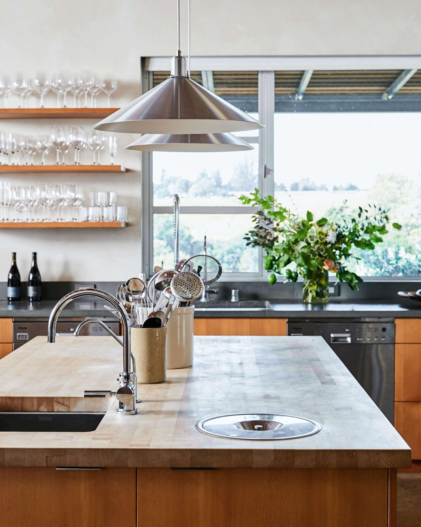 Beyond the central island, two Miele dishwashers flank the main kitchen sink. Outside, deep window overhangs keep the kitchen protected from the hot Sonoma sun.