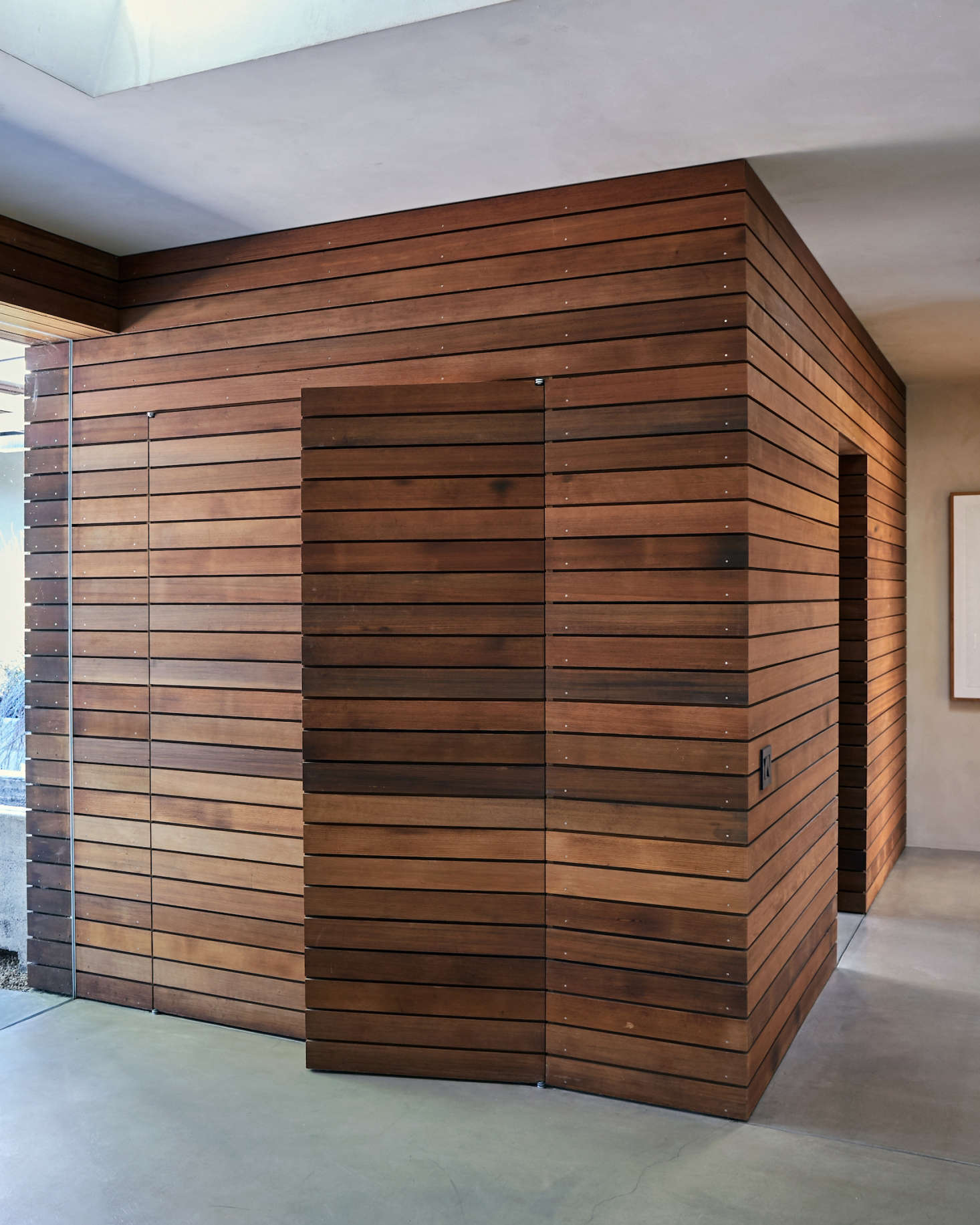 Off the foyer is a utility room (with mudroom and closets) paneled in repurposed wine-barrel redwood that extends continuously from the exterior of the house. Coat closet doors are fully integrated into the paneling: 